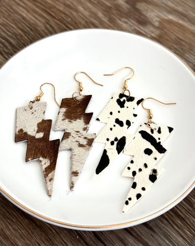 2 pairs of cow print earrings on a white plate